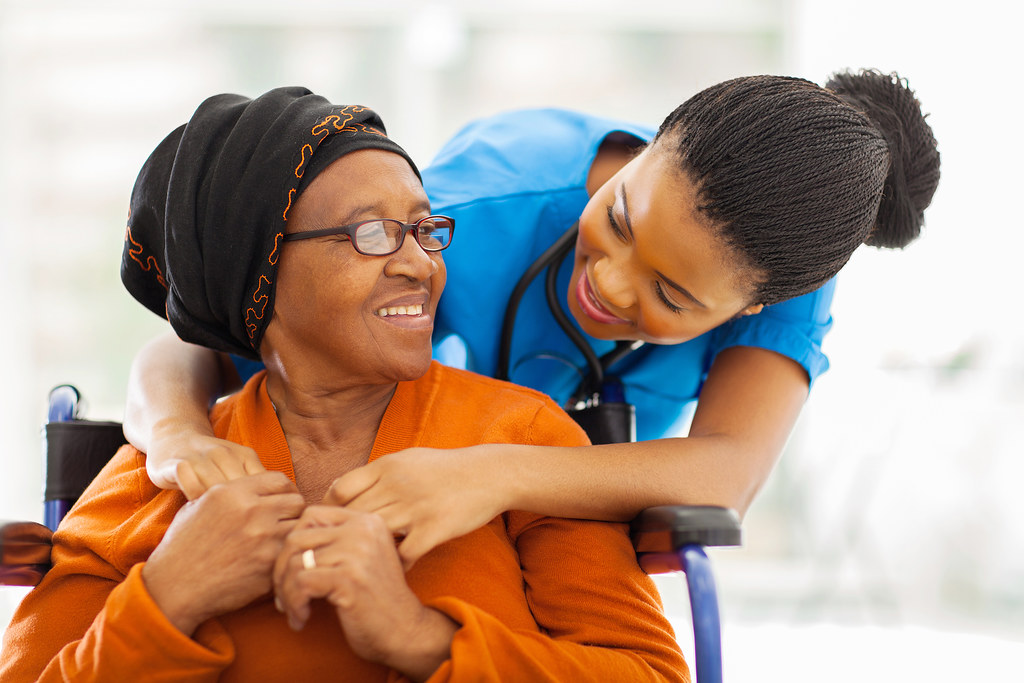 Black nurse carefully reviewing medications with an elderly patient