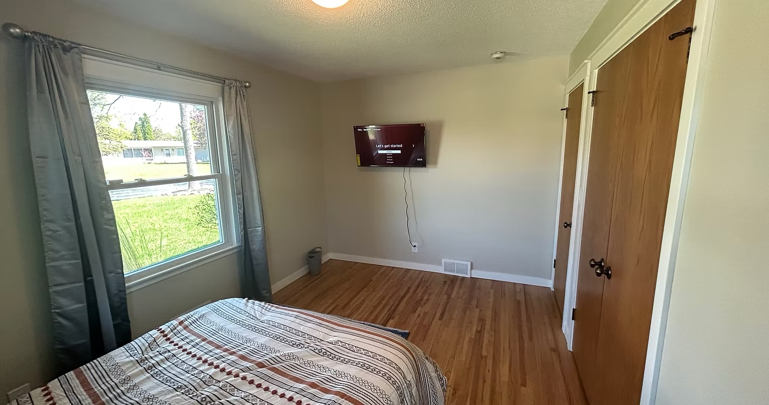 Bedroom with wall-mounted TV and lawn view